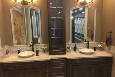 Photo of a large mediterranean ensuite bathroom in New York with raised-panel cabinets, dark wood cabinets, a double shower, beige tiles, travertine tiles, beige walls, a vessel sink, tiled worktops, an open shower, travertine flooring and beige floors.