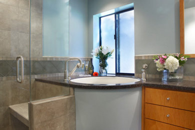 Ispirazione per una stanza da bagno padronale minimal di medie dimensioni con lavabo sottopiano, ante lisce, ante in legno scuro, vasca ad angolo, doccia ad angolo, WC a due pezzi, piastrelle grigie e pareti blu