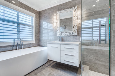 Example of a mid-sized trendy master gray tile and stone tile porcelain tile bathroom design in Vancouver with flat-panel cabinets, white cabinets, an undermount sink, marble countertops, a two-piece toilet and gray walls