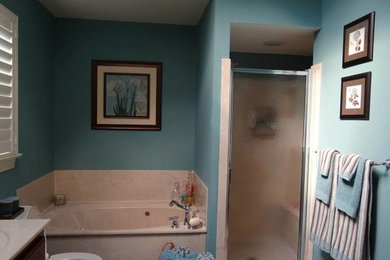 Modelo de cuarto de baño principal con encimera de mármol, bañera esquinera, ducha esquinera y paredes azules