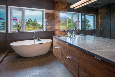 Design ideas for a medium sized contemporary ensuite bathroom in Toronto with a submerged sink, flat-panel cabinets, dark wood cabinets, a freestanding bath, grey tiles, mosaic tile flooring, a corner shower, ceramic tiles, solid surface worktops and grey worktops.