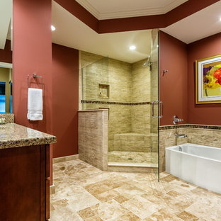 Photo of a large traditional master bathroom in Detroit with an undermount sink, shaker cabinets, an alcove tub, a corner shower, a two-piece toilet, medium wood cabinets, engineered quartz benchtops, multi-coloured tile, stone tile, red walls, travertine floors, beige floor and a hinged shower door.