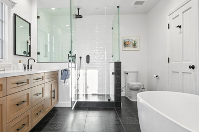 Bild på ett stort vit vitt en-suite badrum, med ett fristående badkar, vit kakel, tunnelbanekakel, vita väggar, klinkergolv i porslin, bänkskiva i kvarts och svart golv