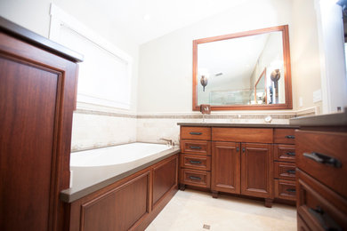 Example of a small classic master beige tile and travertine tile travertine floor and beige floor corner shower design in Sacramento with recessed-panel cabinets, dark wood cabinets, an undermount tub, beige walls, an undermount sink, solid surface countertops and a hinged shower door