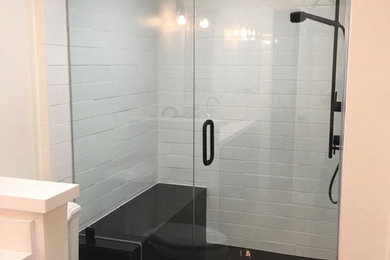 Mid-sized trendy 3/4 medium tone wood floor and brown floor alcove shower photo in Orange County with raised-panel cabinets, black cabinets, a one-piece toilet, white walls, an undermount sink, quartz countertops, a hinged shower door and white countertops