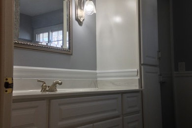 クリーブランドにある低価格の中くらいなトラディショナルスタイルのおしゃれなマスターバスルーム (レイズドパネル扉のキャビネット、白いキャビネット、アルコーブ型シャワー、分離型トイレ、青いタイル、グレーの壁、クッションフロア、一体型シンク、大理石の洗面台、グレーの床、引戸のシャワー、白い洗面カウンター) の写真