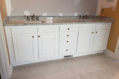 Modelo de cuarto de baño principal, doble y a medida de tamaño medio con armarios con paneles con relieve, puertas de armario blancas, encimera de cuarcita y encimeras beige