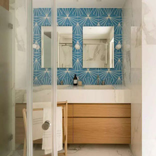 Mid-sized beach style bathroom in Other with flat-panel cabinets, light wood cabinets, a freestanding tub, an open shower, blue tile, porcelain tile, with a sauna, tile benchtops, a hinged shower door, white benchtops, a double vanity, a built-in vanity, white walls, cement tiles, an undermount sink, white floor and brick walls.