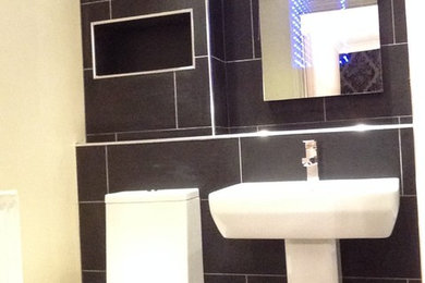 Modern bathroom in West Midlands with a pedestal sink, a two-piece toilet, black tiles, porcelain tiles, black walls and porcelain flooring.