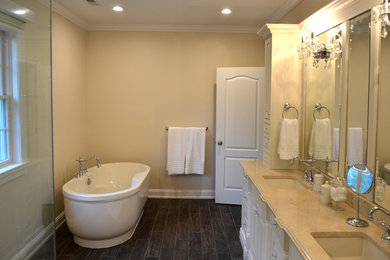This is an example of a large traditional ensuite bathroom in Philadelphia with a submerged sink, freestanding cabinets, marble worktops, a freestanding bath, an alcove shower, a two-piece toilet, beige tiles, stone tiles, beige walls, porcelain flooring and white cabinets.