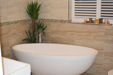 Photo of a small classic bathroom in West Midlands with freestanding cabinets, white cabinets, a freestanding bath, a built-in shower, a two-piece toilet, multi-coloured tiles, ceramic tiles, multi-coloured walls, ceramic flooring, a wall-mounted sink, beige floors and a sliding door.