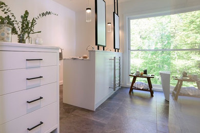Photo of a large contemporary ensuite bathroom in Portland Maine with flat-panel cabinets, white cabinets, a freestanding bath, a double shower, a wall mounted toilet, white tiles, ceramic tiles, white walls, ceramic flooring, a submerged sink, marble worktops, grey floors and a hinged door.