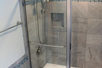 リッチモンドにある中くらいなトランジショナルスタイルのおしゃれなマスターバスルーム (落し込みパネル扉のキャビネット、白いキャビネット、シャワー付き浴槽	、グレーのタイル、セラミックタイル、白い壁、セラミックタイルの床、グレーの床、アルコーブ型浴槽、分離型トイレ、御影石の洗面台、引戸のシャワー、ベッセル式洗面器) の写真
