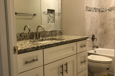 Inspiration for a small transitional master ceramic tile, beige floor and single-sink bathroom remodel in Other with white cabinets, a one-piece toilet, beige walls, an undermount sink, gray countertops, a freestanding vanity, shaker cabinets and granite countertops
