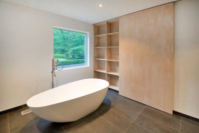 Ejemplo de cuarto de baño moderno con bañera exenta, paredes beige, suelo de pizarra y suelo gris