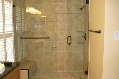 Example of a large master beige tile and stone tile alcove shower design in Baltimore with a drop-in sink, recessed-panel cabinets, medium tone wood cabinets, granite countertops and beige walls