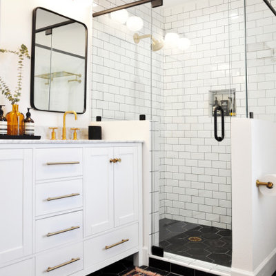 Inspiration for a transitional 3/4 white tile and subway tile black floor corner shower remodel in Orlando with shaker cabinets, white cabinets, white walls, an undermount sink, a hinged shower door and multicolored countertops