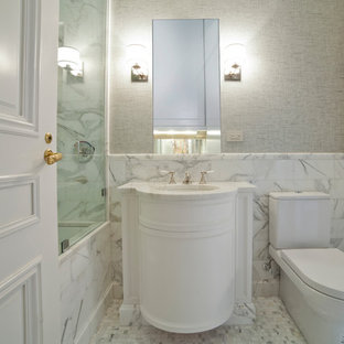 Inspiration for a mid-sized traditional master bathroom in New York with raised-panel cabinets, an alcove shower, a bidet, white tile, metal tile, grey walls, vinyl floors, an undermount sink, marble benchtops, grey floor, a hinged shower door and white benchtops.