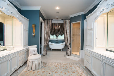 Mid-sized elegant master beige floor bathroom photo in New Orleans with raised-panel cabinets, white cabinets, blue walls, a drop-in sink and a hinged shower door