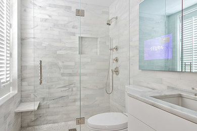 Modern inredning av ett litet en-suite badrum, med ett undermonterad handfat, vita skåp, marmorbänkskiva, vit kakel, stenkakel, marmorgolv och släta luckor