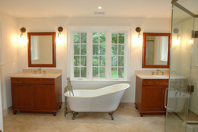 Foto de cuarto de baño principal clásico renovado de tamaño medio con armarios con paneles con relieve, puertas de armario de madera en tonos medios, bañera con patas, ducha empotrada, sanitario de dos piezas, paredes beige, suelo de piedra caliza, lavabo bajoencimera, encimera de granito, suelo beige y ducha con puerta con bisagras