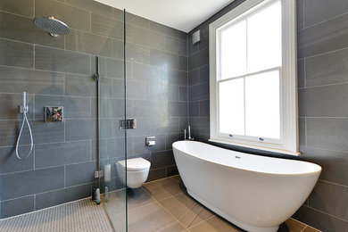 Inspiration for a medium sized modern family bathroom in London with flat-panel cabinets, dark wood cabinets, a freestanding bath, a walk-in shower, a one-piece toilet, black tiles, ceramic tiles, black walls, ceramic flooring, a built-in sink, tiled worktops, black floors and an open shower.