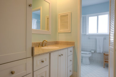 Imagen de cuarto de baño actual de tamaño medio con armarios estilo shaker, puertas de armario blancas, sanitario de una pieza, paredes azules, encimera de cuarzo compacto, suelo de baldosas de porcelana y lavabo bajoencimera