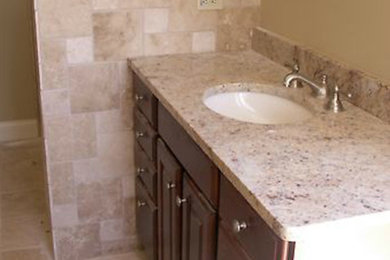 Mid-sized 3/4 beige tile and porcelain tile porcelain tile corner shower photo in St Louis with an undermount sink, raised-panel cabinets, medium tone wood cabinets, granite countertops and beige walls