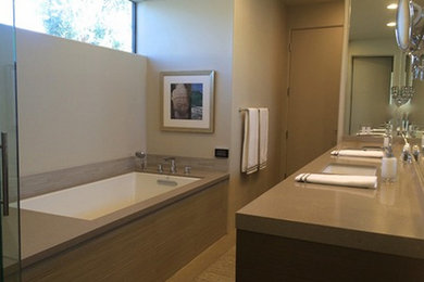 Example of a master beige tile and stone slab light wood floor bathroom design in Other with an undermount sink, flat-panel cabinets, dark wood cabinets, solid surface countertops and beige walls