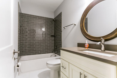 Example of a mid-sized trendy kids' brown tile and glass tile porcelain tile and white floor bathroom design in Atlanta with a one-piece toilet, an undermount sink, shaker cabinets, white cabinets, gray walls, quartzite countertops and brown countertops