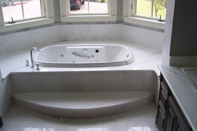 Modelo de cuarto de baño tradicional con lavabo encastrado, armarios con paneles empotrados, puertas de armario blancas, bañera encastrada y baldosas y/o azulejos blancos