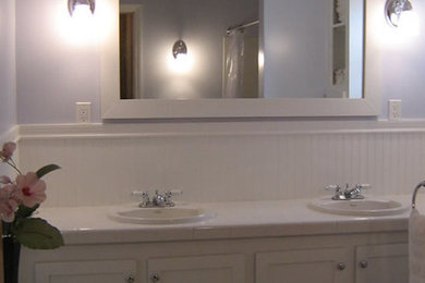 Mid-sized elegant 3/4 white tile bathroom photo in New York with a drop-in sink, recessed-panel cabinets, white cabinets, tile countertops and blue walls