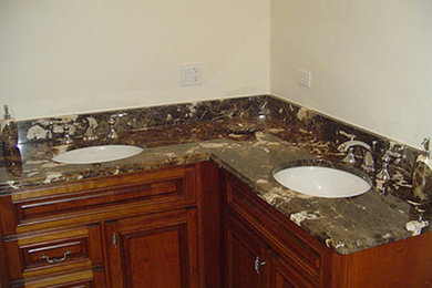 Imagen de cuarto de baño principal de tamaño medio con lavabo encastrado, armarios con paneles con relieve, puertas de armario de madera oscura, encimera de granito y paredes beige