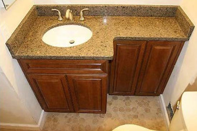 Cette photo montre une salle de bain chic en bois brun avec un placard avec porte à panneau surélevé, un plan de toilette en marbre, une baignoire posée, un carrelage beige et un sol en carrelage de céramique.