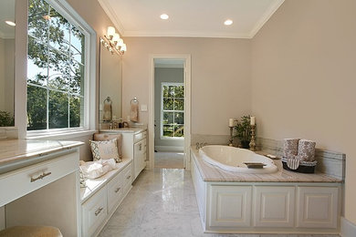 Large elegant master white tile and stone tile marble floor drop-in bathtub photo in New Orleans with an undermount sink, raised-panel cabinets, white cabinets, marble countertops and beige walls