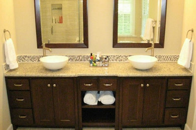 Imagen de cuarto de baño principal grande con lavabo sobreencimera, puertas de armario de madera en tonos medios, encimera de granito, ducha esquinera, baldosas y/o azulejos multicolor, paredes beige y suelo de baldosas de cerámica