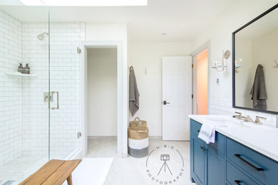 Bild på ett mellanstort vit vitt en-suite badrum, med luckor med infälld panel, blå skåp, ett undermonterat badkar, en dusch i en alkov, vit kakel, tunnelbanekakel, beige väggar, ett undermonterad handfat, grått golv och dusch med gångjärnsdörr