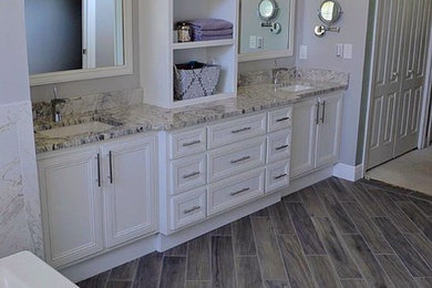 Large transitional master laminate floor and brown floor alcove bathtub photo in Other with recessed-panel cabinets, white cabinets, beige walls, an undermount sink, quartz countertops and white countertops