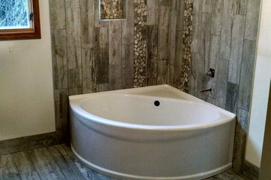 Modelo de cuarto de baño principal rústico de tamaño medio con bañera esquinera, combinación de ducha y bañera, baldosas y/o azulejos blancos, paredes blancas, suelo laminado, suelo gris y ducha abierta