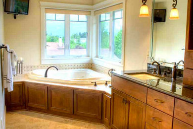 Inspiration for a large master beige tile and stone tile travertine floor corner bathtub remodel in New York with flat-panel cabinets, medium tone wood cabinets, granite countertops and beige walls