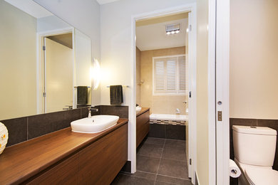 Idée de décoration pour une salle de bain design en bois brun avec une baignoire posée, une douche ouverte, WC à poser, un carrelage gris, des carreaux de porcelaine, un mur vert, un sol en vinyl, un lavabo posé et un plan de toilette en stratifié.
