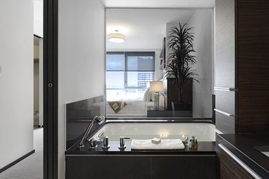 Modelo de cuarto de baño contemporáneo con armarios con paneles lisos, puertas de armario de madera en tonos medios y baldosas y/o azulejos negros