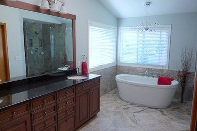 Bild på ett badrum, med ett undermonterad handfat, luckor med infälld panel, skåp i mörkt trä, bänkskiva i onyx, ett fristående badkar, blå väggar och marmorgolv