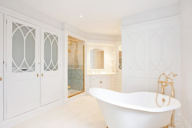 This is an example of a large traditional bathroom in London with white walls, white cabinets, a claw-foot bath, an alcove shower, a built-in sink, a hinged door and raised-panel cabinets.