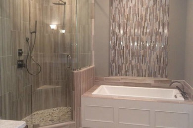 This is an example of a large traditional ensuite bathroom in New Orleans with flat-panel cabinets, an alcove shower, a one-piece toilet, beige tiles, beige walls and light hardwood flooring.