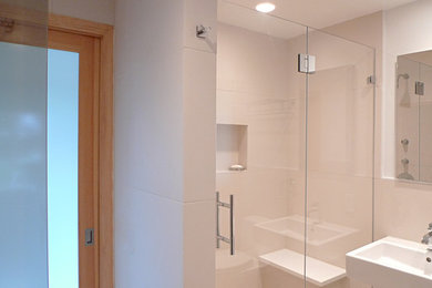 ニューヨークにある中くらいなコンテンポラリースタイルのおしゃれなバスルーム (浴槽なし) (フラットパネル扉のキャビネット、コーナー設置型シャワー、白いタイル、磁器タイル、ベージュの壁、一体型シンク、クオーツストーンの洗面台、開き戸のシャワー、白い洗面カウンター) の写真