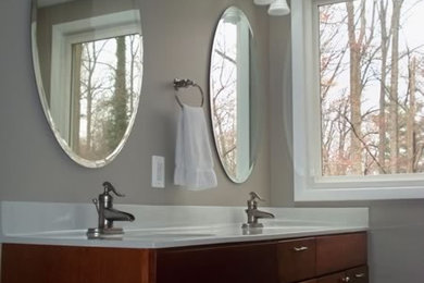 Ejemplo de cuarto de baño principal de tamaño medio con lavabo integrado, armarios con paneles lisos, puertas de armario de madera en tonos medios y paredes grises