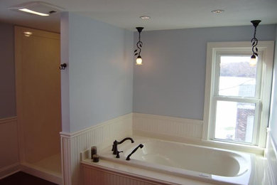 クリーブランドにある小さなおしゃれなバスルーム (浴槽なし) (白いキャビネット、アルコーブ型浴槽、コーナー設置型シャワー、一体型トイレ	、白いタイル、青い壁、無垢フローリング) の写真