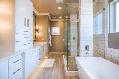 Inspiration for a large modern ensuite bathroom in Phoenix with flat-panel cabinets, white cabinets, a freestanding bath, a walk-in shower, a one-piece toilet, white tiles, metro tiles, grey walls, porcelain flooring, a submerged sink, quartz worktops, grey floors and an open shower.