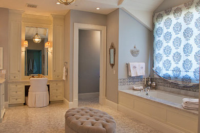 Пример оригинального дизайна: большая главная ванная комната в классическом стиле с фасадами с утопленной филенкой, бежевыми фасадами, полновстраиваемой ванной, серыми стенами, полом из мозаичной плитки, врезной раковиной, мраморной столешницей и коричневым полом